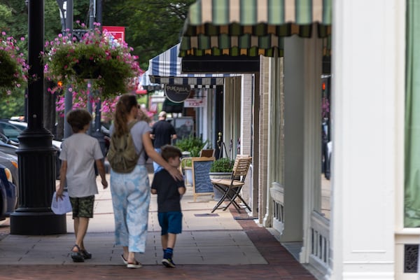 Pedestrians walk in downtown Newnan on Wednesday, July 2, 2025, alongside the building that holds First Liberty Building & Loan. (Arvin Temkar/AJC)