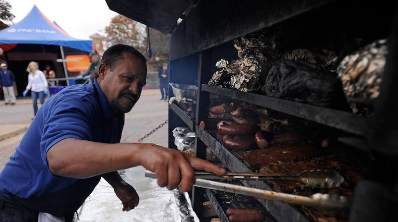 Williamson Bros. chef Juan Mendez checks on the barbecue at a Smyrna Fall Jonquil Festival on the Smyrna Village Green in this file photo.
