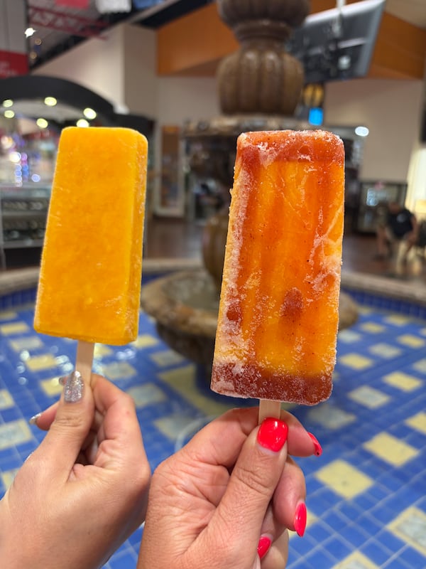 Two different people's hands each hold up separate popsicles for the photo