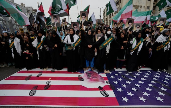 Shiite Muslims stand over a representation of U.S flag during a rally to condemn Israeli strikes on Iran, in Karachi, Pakistan, Sunday, June 22, 2025. (AP Photo/Fareed Khan)