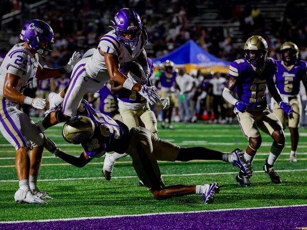 Cartersville wide receiver Madoxx Davis dives over Hiram safety Dorian Robinson for a touchdown on Friday, Aug. 21, 2026, in Hiram. (Erik S. Lesser for the AJC)