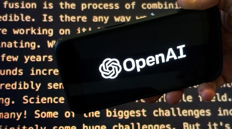 FILE - The OpenAI logo appears on a mobile phone in front of a screen showing part of the company website in this photo taken on Nov. 21, 2023 in New York. (AP Photo/Peter Morgan, File)