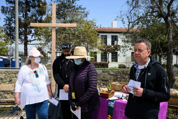Members of a church listen to a prayer by Pastor John Shaver, right, during a Cross Walk event by the Community United Methodist Church of the Pacific Palisades, Friday, April 18, 2025, in the Pacific Palisades area of Los Angeles. (AP Photo/William Liang)