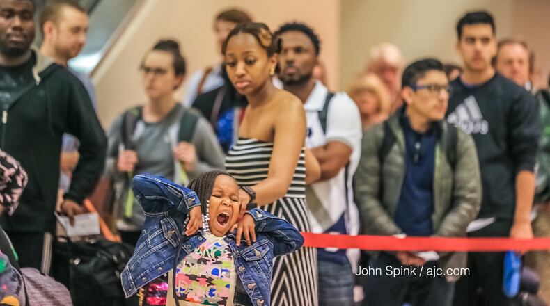 Milani Kinos, 4, with mother Michelle Rustin wait in long lines at Hartsfield-Jackson International Airport Thursday as the Memorial Day travel holiday is underway. Photo: JOHN SPINK /JSPINK@AJC.COM