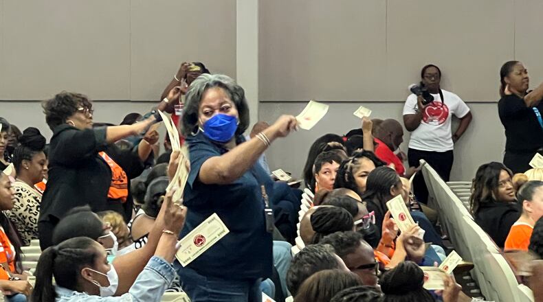 Employees in the DeKalb County School District celebrate the early distribution of retention bonuses on Friday, Oct. 6, 2023, at the district office in Stone Mountain. The bonuses were represented by printed $2,000 bills, signed by Superintendent Devon Horton and bearing the message, "Employees are the heart of DeKalb schools." (Cassidy Alexander / Cassidy.Alexander@ajc.com)
