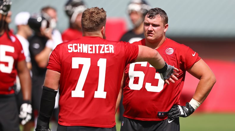 Falcons rookie offensive lineman Chris Lindstrom (right) gets some pointers from guard Wes Schweitzer during the first practice of training camp Monday, July 22, 2019, in Flowery Branch.