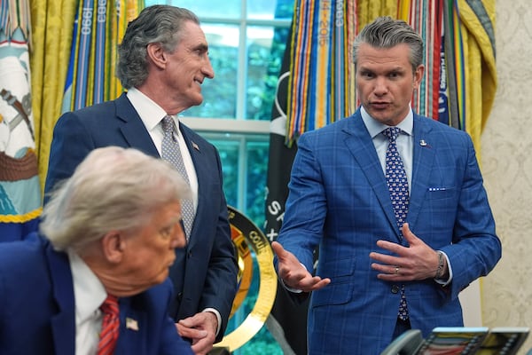 President Donald Trump and Interior Secretary Doug Burgum listen as Defense Secretary Pete Hegseth speaks before Trump signed executive orders regarding nuclear energy in the Oval Office of the White House, Friday, May 23, 2025, in Washington. (AP Photo/Evan Vucci)