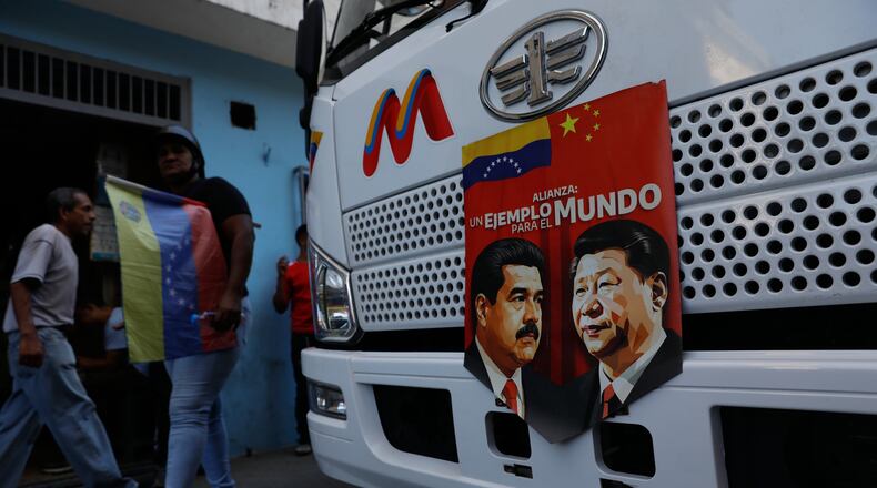 A banner on the front end of a bus features images of Venezuelan President Nicolas Maduro and China's Xi Jinping with a message that reads in Spanish: "An example for the world," during a government-organized rally opposing U.S. intervention, in Caracas, Venezuela, Saturday, Dec. 13, 2025. (AP Photo/Cristian Hernandez)