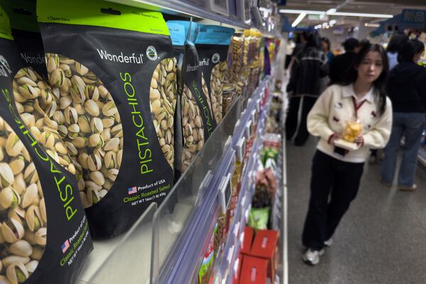 People walk by shelf displaying imported nuts from the United States, at the Hema supermarket, in Beijing, Tuesday, April 8, 2025. (AP Photo/Andy Wong)