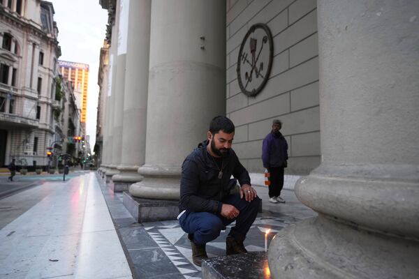 Agustín Hartich lights a candle at the Cathedral following the Vatican's announcement of Pope Francis' death in Buenos Aires, Argentina, Monday, April 21, 2025. (AP Photo/Natacha Pisarenko)