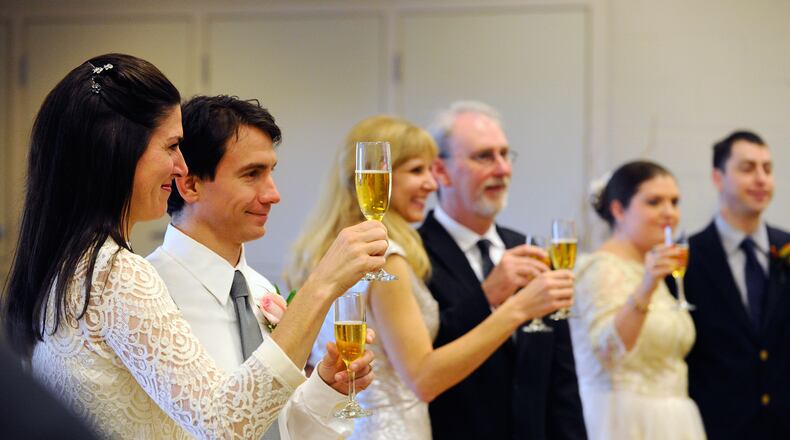 Newlyweds Katharine and Victor Serrano, left, join other couples for a champagne toast after exchanging vows during a mass wedding at Pinckneyville Park Community Recreation Center in Norcross in this 2014 file photo.