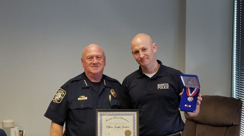 Marietta police chief Dan Flynn, left, recognized office Joe Jenkins for saving the life of a man who had been shot and left for dead.