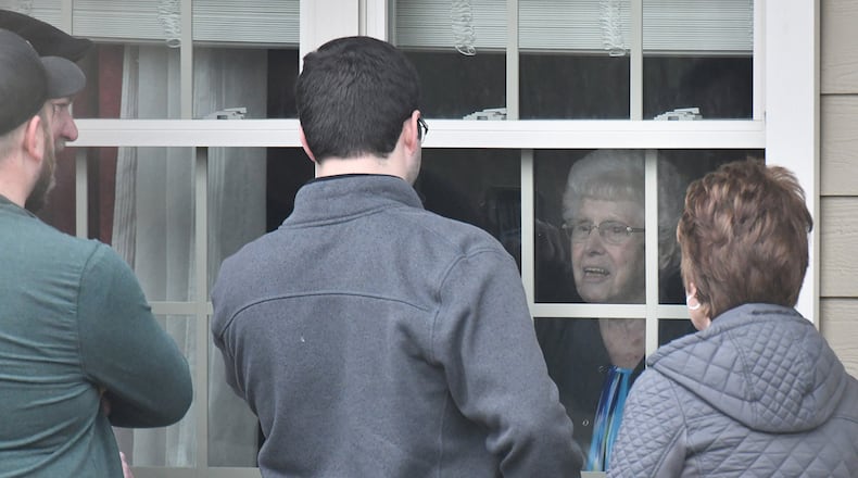 Family members visit a relative through the window at The Retreat at Canton after delivering a birthday balloon and a gift bag. Three residents and an employee of the home have “tested presumptively positive” for COVID-19. Residents are self-isolating in their rooms, and the home is not admitting visitors. (Hyosub Shin / Hyosub.Shin@ajc.com)