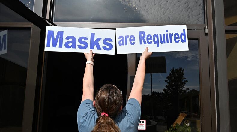 Mary Beth McKenna, director of religious education, posts signs on May 23, 2020, ahead of daily Mass resuming at St. Benedict Catholic Church in metro Atlanta. (Hyosub Shin / Hyosub.Shin@ajc.com)