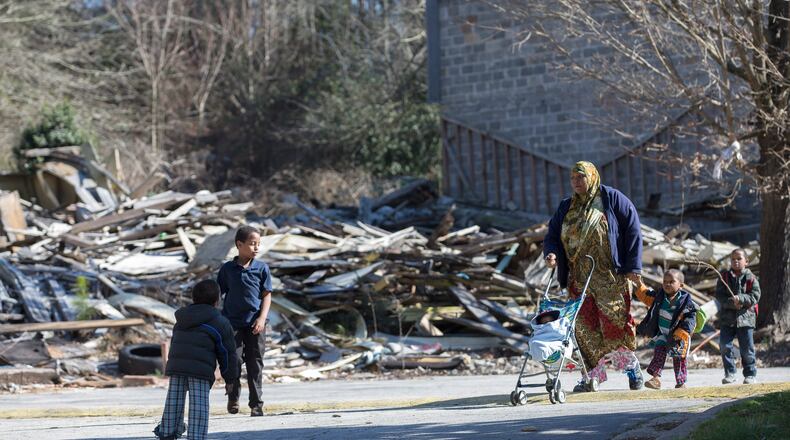 Olympia Thompson walks her five boys past the remains of one of the burned out units in the Brannon Hill community in this AJC file photo.
