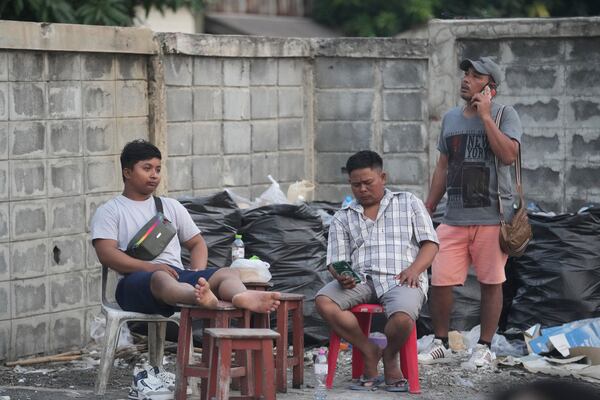 Relatives of workers at a high-rise building under construction that collapsed after a strong earthquake wait as rescuers search for victims, in Bangkok, Thailand, Saturday, March 29, 2025. (AP Photo/Sakchai Lalit)