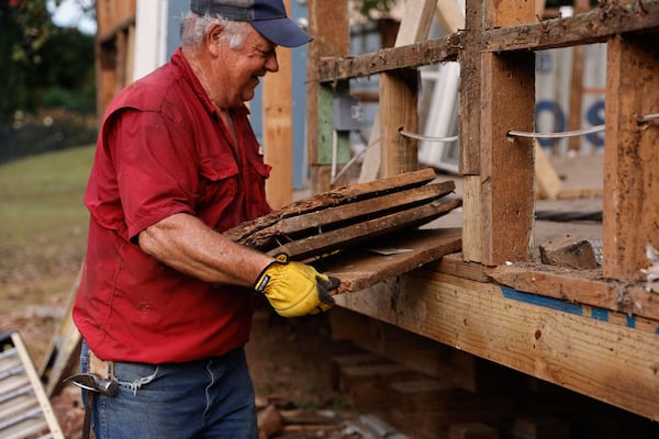 A construction worker holds pieces of wood at the deconstruction site of Doc’s Café in Roswell. (Natrice Miller/ AJC)