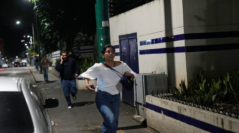 Pedestrians run after explosions and low-flying aircraft were heard in Caracas, Venezuela, Saturday, Jan. 3, 2026. (AP Photo/Matias Delacroix)