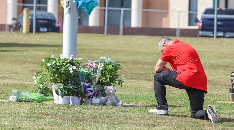 A mourner pays tribute tot the Apalachee High School shooting victims. (John Spinks/The Atlanta Journal-Constitution)