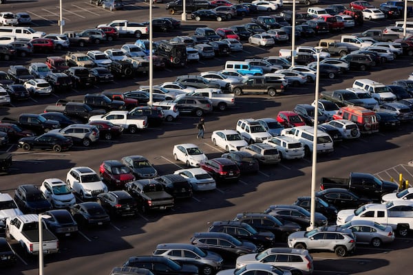 FILE - A person walks through a parking lot at Harry Reid International Airport, Wednesday, April 9, 2025, in Las Vegas. (AP Photo/John Locher, File)