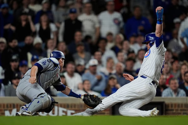 Chicago Cubs left fielder Ian Happ (8), right, is tagged out at home base by Los Angeles Dodgers catcher Will Smith (16) during the sixth inning of a baseball game Tuesday, April 22, 2025, in Chicago. (AP Photo/Erin Hooley)