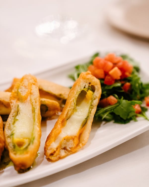 Cheesy zucchini blossoms and a side salad on a plate at Amalfi Cucina.