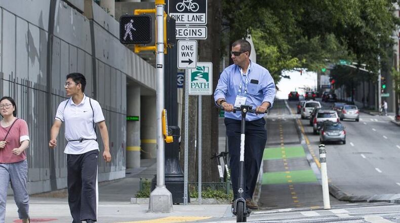 A man rides a shareable e-scooter along Centennial Olympic Park Drive last year. (Alyssa Pointer/alyssa.pointer@ajc.com)