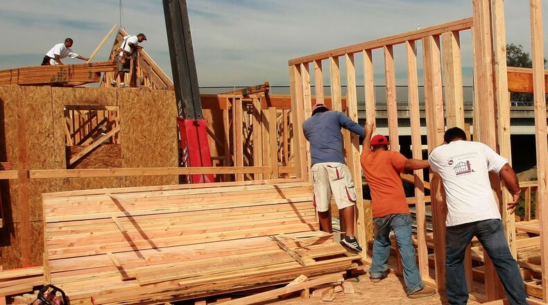 Construction workers build the frame of a house at a new housing development.