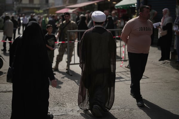 A Shiite cleric arrives to vote at a polling station as Lebanese army soldiers secure the area during municipal elections in the southern suburbs of Beirut, Lebanon, Sunday, May 4, 2025. (AP Photo/Hassan Ammar)