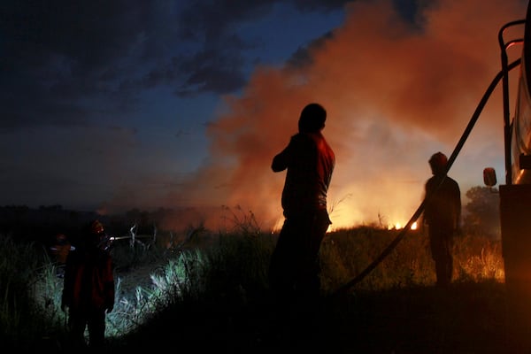 Firemen attempt to extinguish a fire that razes through a peatland field in Ogan Ilir, South Sumatra, Indonesia, Sunday, July 20, 2025. (AP Photo/Muhammad Hatta)