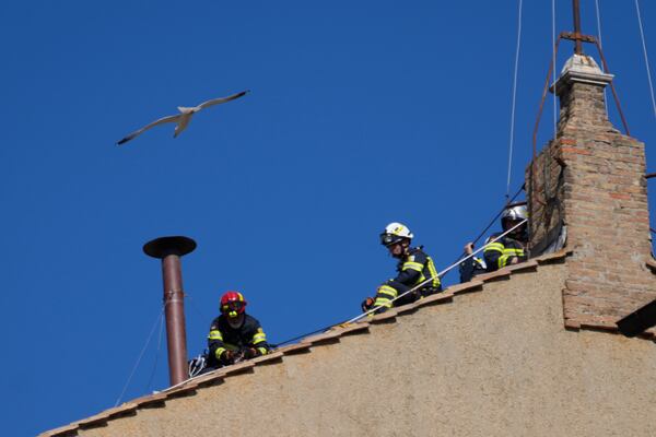 Firefighters place the chimney on the roof of the Sistine Chapel, where cardinals will gather to elect the new pope, at the Vatican, Friday, May 2, 2025. (AP Photo/Gregorio Borgia)