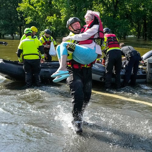 FILE - Conroe firefighter Cody Leroy carries a resident evacuated in a boat by the CFD Rapid Intervention Team from her flooded home in the aftermath of a severe storm May 2, 2024, in Conroe, Texas. (Brett Coomer/Houston Chronicle via AP)