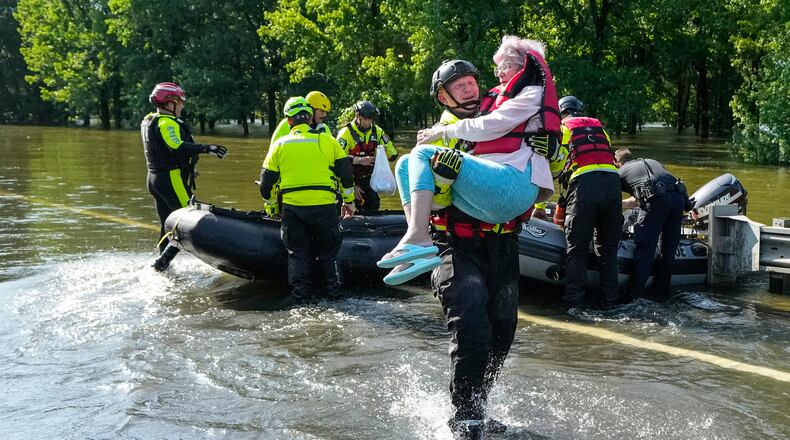 FILE - Conroe firefighter Cody Leroy carries a resident evacuated in a boat by the CFD Rapid Intervention Team from her flooded home in the aftermath of a severe storm May 2, 2024, in Conroe, Texas. (Brett Coomer/Houston Chronicle via AP)