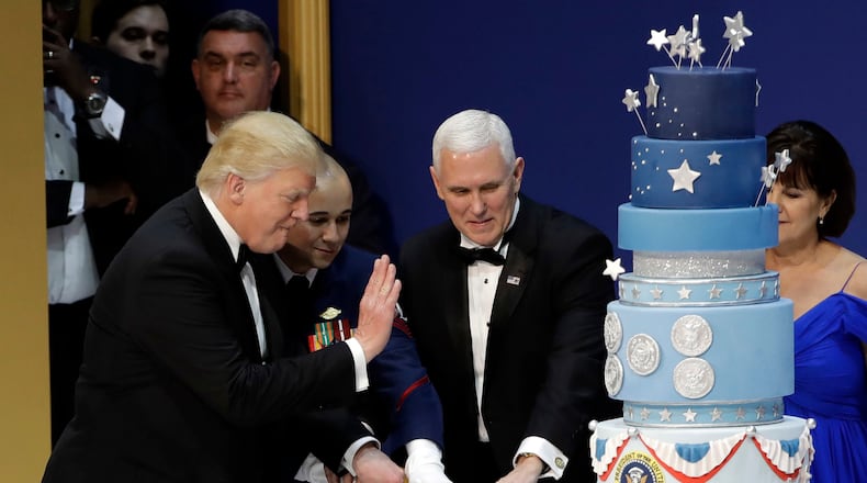 President Donald J. Trump, left, and Vice President Mike Pence, right, are helped by Coast Guard Petty Officer 2nd Class Matthew Babot, center, as they cut a cake at The Salute To Our Armed Services Inaugural Ball Friday, Jan. 20, 2017, in Washington. (AP Photo/David J. Phillip)