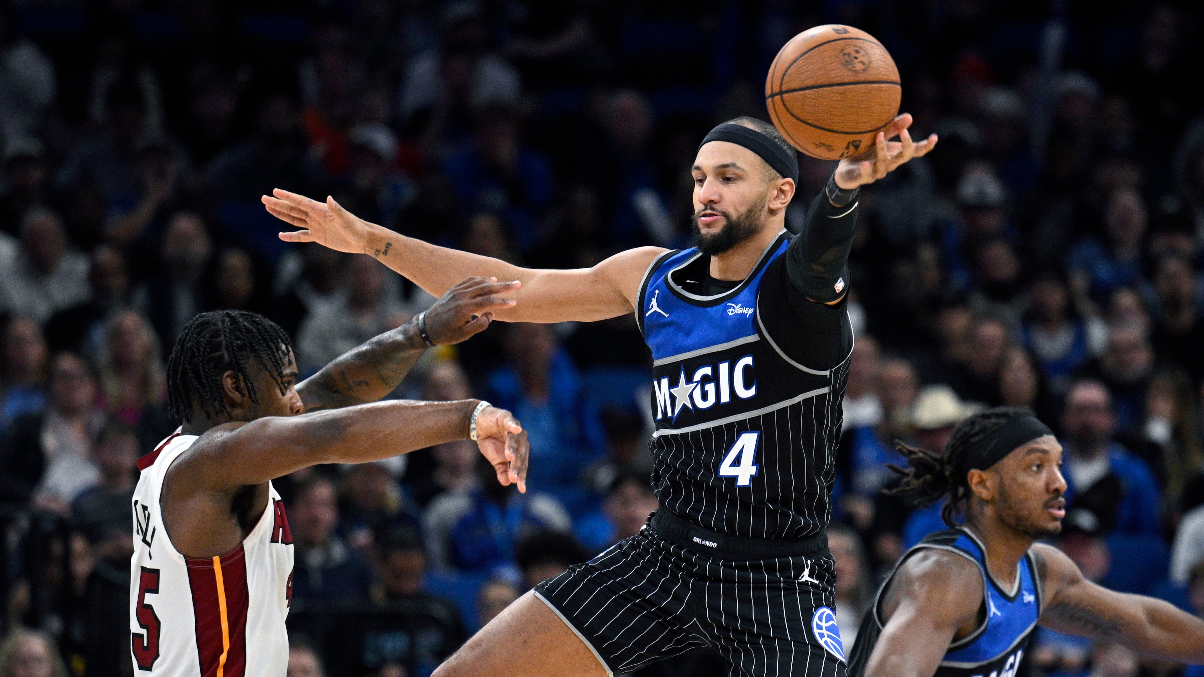 Orlando Magic guard Jalen Suggs (4) deflects a pass by Miami Heat guard Davion Mitchell, left, during the second half of an NBA Cup basketball game, Tuesday, Dec. 9, 2025, in Orlando, Fla. (AP Photo/Phelan M. Ebenhack)
