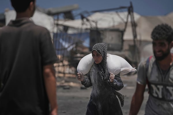 Palestinians carry sacks of flour unloaded from a humanitarian aid convoy that reached Gaza City from the northern Gaza Strip, Tuesday, July 22, 2025. (AP Photo/Jehad Alshrafi)