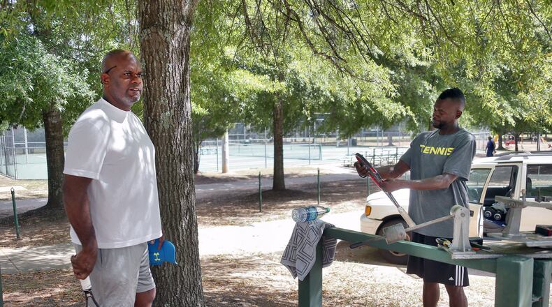 Darrell Hooker (left), prepares for a tennis lesson with Scott Ross at Trammell Crow Park. “I want to know how they are going to enforce it” Ross said of the smoking ban. BOB ANDRES /BANDRES@AJC.COM