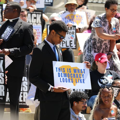 A protestor stands outside the South Carolina Statehouse on Thursday, May 14, 2026, in Columbia, S.C. (AP Photo/Jeffrey Collins)