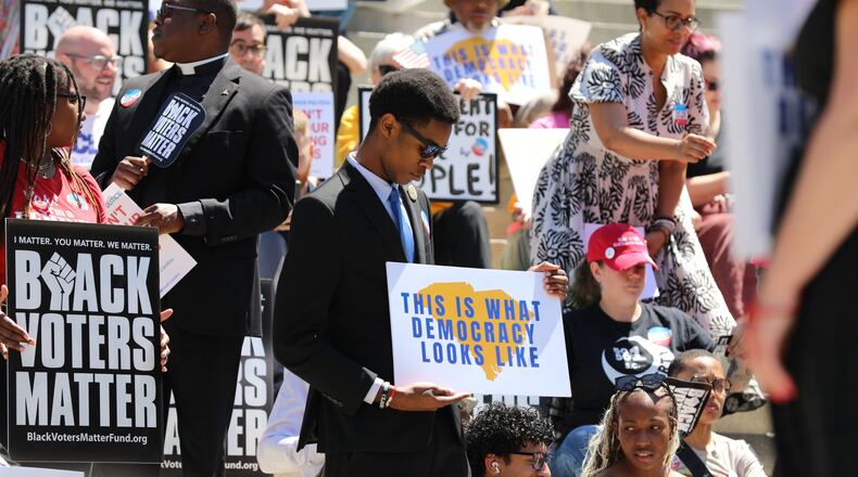 A protestor stands outside the South Carolina Statehouse on Thursday, May 14, 2026, in Columbia, S.C. (AP Photo/Jeffrey Collins)