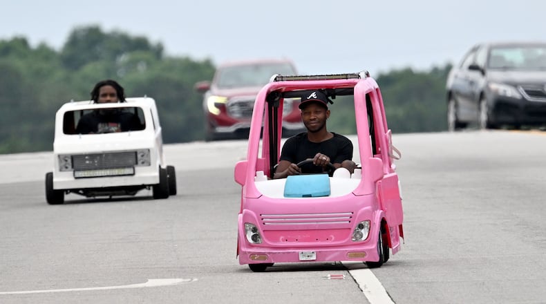 Mali “Sota” Hightower drives his modified, gas-powered Barbie Dream camper as his friend Marvelous Gainey follows close behind in his modified minicar on Tuesday, June 9, 2026, in Ellenwood. Hightower decided to put his interest in modified kids' cars to use when gas prices began to rise, driving the pink vehicle to his day job as a contractor. (Hyosub Shin/AJC)