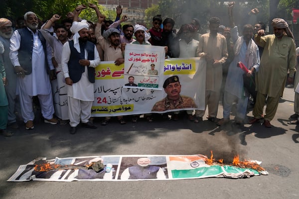 Members of the Awami Rickshaw Union chant slogans next to a burning poster of Indian prime minister Narendra Modi and a Indian flag during a demonstration against the suspension of water-sharing treaty by India with Pakistan, in Lahore, Pakistan, Sunday, April 27, 2025. (AP Photo/K.M. Chaudary)
