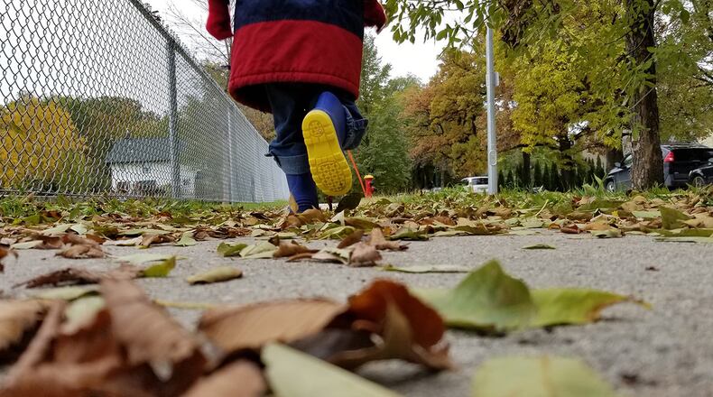 Stock photo of a toddler running on a sidewalk.