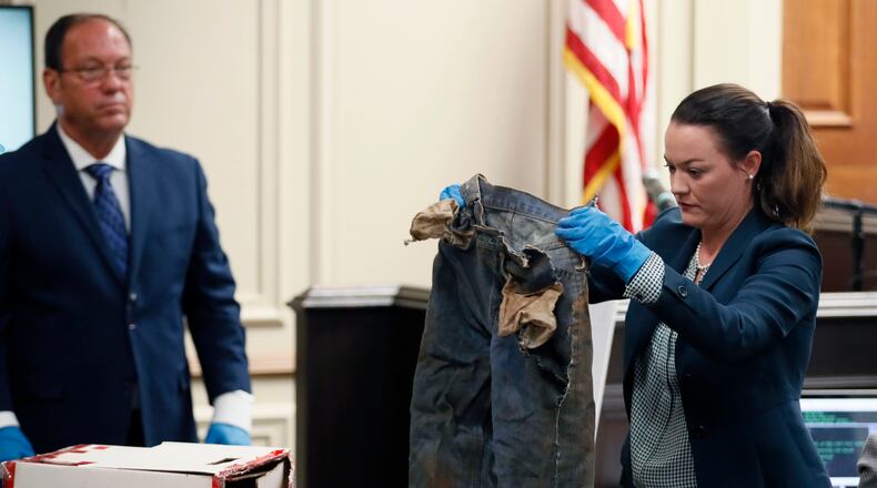 2/14/18 - Griffin - Larry Peterson (left), GBI forensic investigator, watches as Marie Broder, assistant district attorney, shows the jury some of the victim’s clothing that was recovered from the scene. BOB ANDRES /BANDRES@AJC.COM