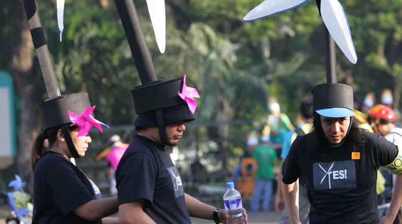 FILE -Participants wear wind turbine headgear to raise peoples awareness on renewable energy, fix their costumes during the Global Day of Action Against Climate Change ,Dec. 8, 2007 in suburban Quezon City, north of Manila, Philippines. (AP Photo/Pat Roque, File)