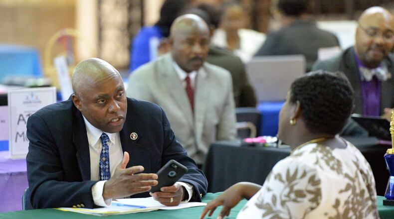 Rodney Swanson, principal of Arabia Mountain High School, talks with a prospective candidate as teachers interview during a job fair earlier this month. KENT D. JOHNSON / AJC