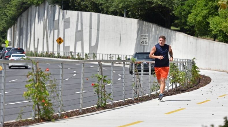 Nick Huston, of Sandy Springs, jogs on the PATH400 trail along Ga. 400 in Buckhead. Sandy Springs has approved a design contract to extend the trail north from Loridans Drive to the Glenridge Connector area. HYOSUB SHIN / HSHIN@AJC.COM