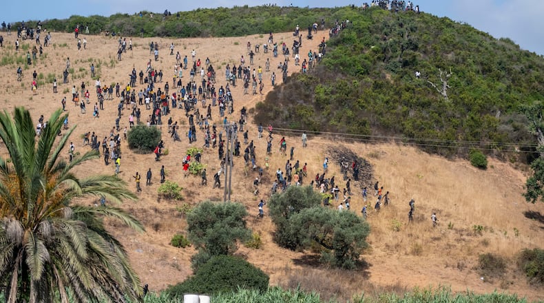 Migrants gather on a hill as they attempt crossing from the border town of Fnideq to the Spanish enclave of Ceuta, Saturday, Aug. 15, 2026. (AP Photo)