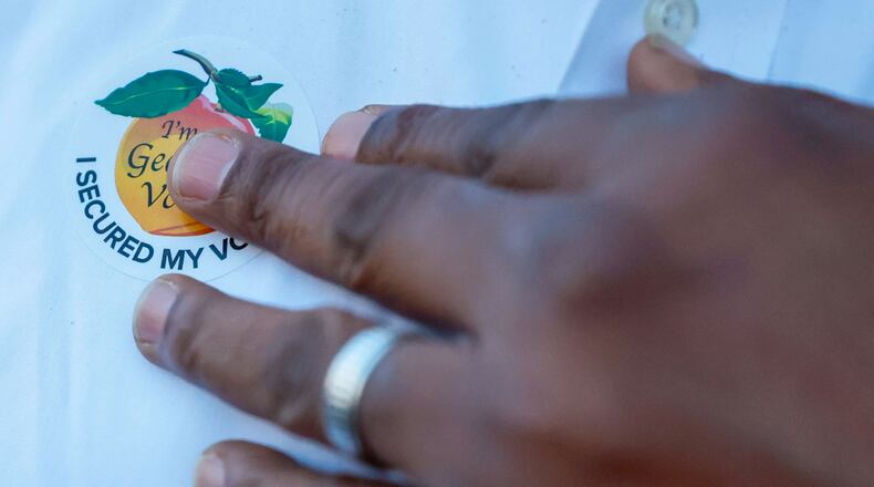 A voter puts on his sticker after casting his ballot at the Evergreen Baptist Church during the Georgia presidential primary elections on Tuesday, March 12, 2024. Miguel Martinez /miguel.martinezjimenez@ajc.com