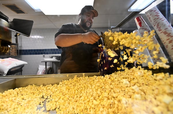 J.R. Arellano prepares to fill up a customer's popcorn bag at a concessions stand of Starlight Drive-In Theatre, Friday, June 13, 2025, in Atlanta. (Hyosub Shin / AJC)