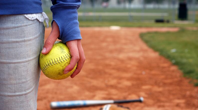 A girl holds a softball on the infield diamond.
